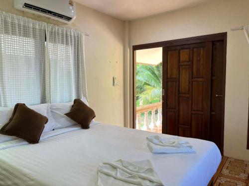 a bedroom with a large white bed with a window at Yao noi cozy home in Ko Yao Noi