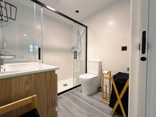 a bathroom with a toilet and a glass shower at Casa da Escola in Combarro