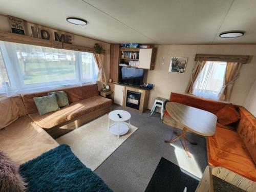 a living room with a couch and a tv at Caravan Turnberry 2 , Seton Sands, Wifi in Port Seton