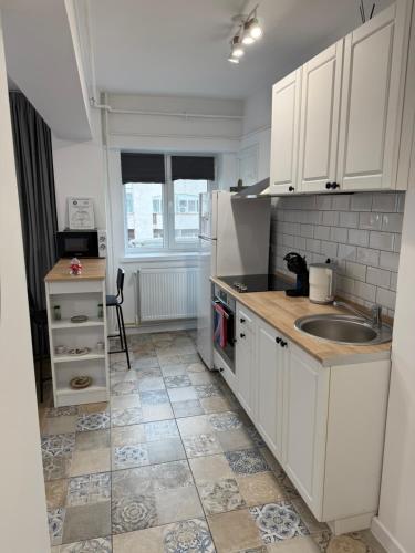 a small kitchen with white cabinets and a sink at Central Studio Yoko , Craiova in Craiova