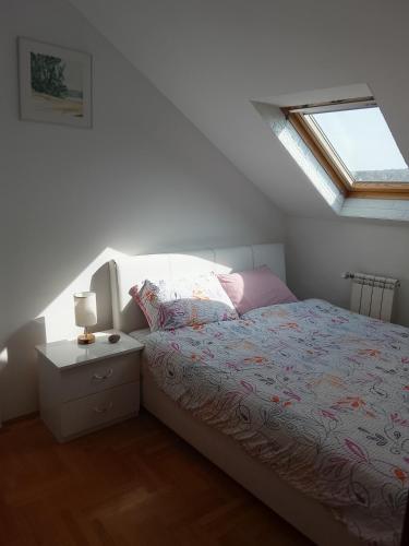 a white bedroom with a bed and a window at Apartman Skyview in Požarevac