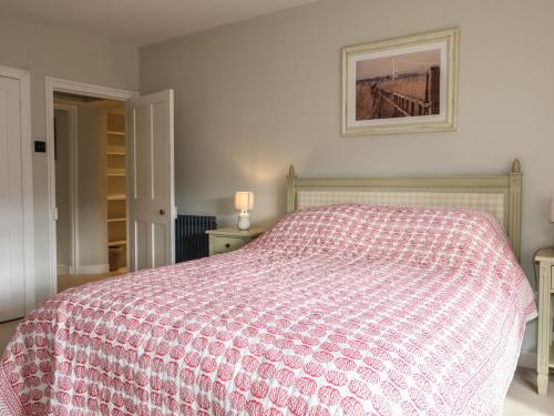 a bedroom with a bed with a red and white comforter at Rectory Cottage in Alton