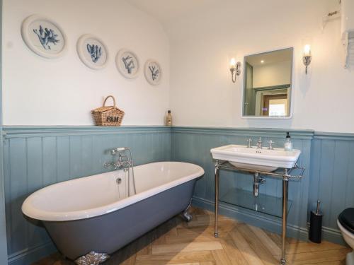 a blue and white bathroom with a tub and a sink at Rectory Cottage in Alton