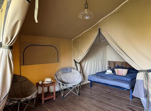 a bedroom with a tent with a bed and a chair at Camping Le Soleil du Verdon in Esparron-de-Verdon