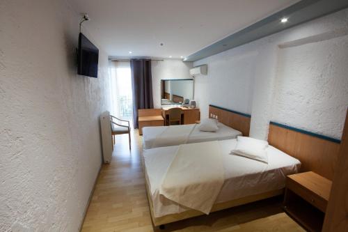 a bedroom with two beds and a table and a chair at Thomas Beach Hotel in Nea Makri