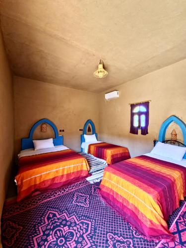 two beds in a room with a rug at Hamada Kem-Kem Tafraoute in Tafraoute Sidi Ali