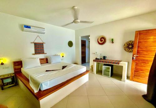 a bedroom with a large bed and a desk at Aluna Beach House Nungwi in Nungwi