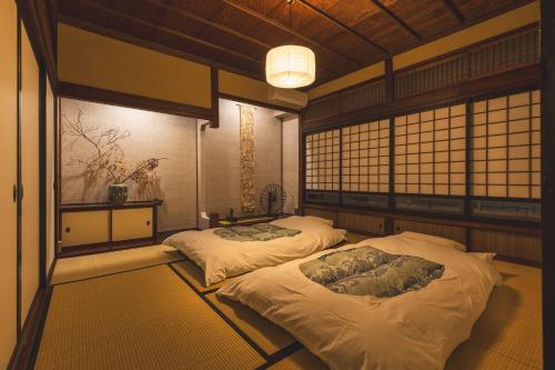 two beds in a room with a room with windows at 城下町の一棟貸し 今来 Konrai - Private-use guesthouse in Matsumoto