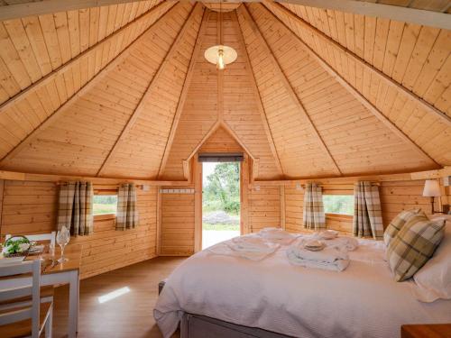 a bedroom with a large bed in a wooden room at Little Luxe Lodges 1 in Kyle of Lochalsh