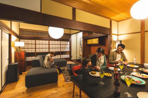 a group of people sitting at a table in a living room at 城下町の一棟貸し 今来 Konrai - Private-use guesthouse in Matsumoto
