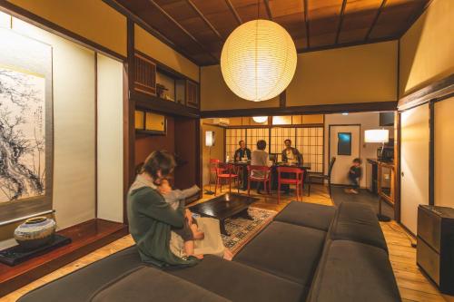 a woman sitting on a couch in a living room at 城下町の一棟貸し 今来 Konrai - Private-use guesthouse in Matsumoto
