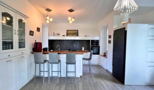 a kitchen with white cabinets and a island with bar stools at Domaine de Treuillaud in Villers-les-Ormes
