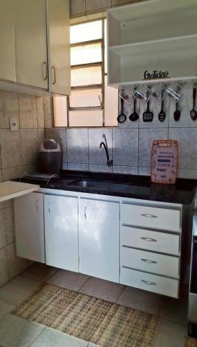 a kitchen with white cabinets and a sink at Praticidade e conforto á poucos passos do aereoporto in Várzea Grande