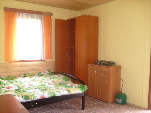 a bedroom with a bed and a dresser and a window at Chatová osada Budín u Žirovnice in Žirovnice