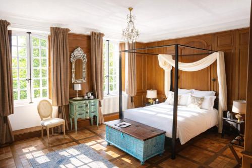 a bedroom with a canopy bed and a table at Manoir la Meffrais 1741-Chambres d'hôtes à 3 min de Dinan-Parking Privé in Dinan
