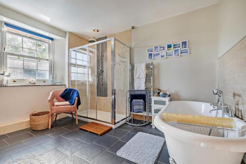 a bathroom with a tub and a shower and a chair at 3 Bed in Uphill oc-n27747 in Linkinhorne