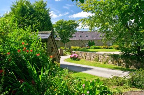 a garden with a stone building and flowers at Beech Cottage - Spacious Cottage with Pool Near Coastal Trails in HAW