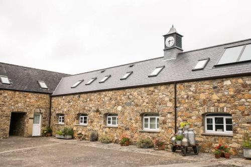 a stone building with a clock tower on top of it at Barn Cottage - Family-Friendly Cottage with Heated Indoor Pool in Haverfordwest