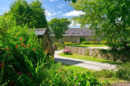 a garden with a stone building and flowers at Barn Cottage - Family-Friendly Cottage with Heated Indoor Pool in Haverfordwest