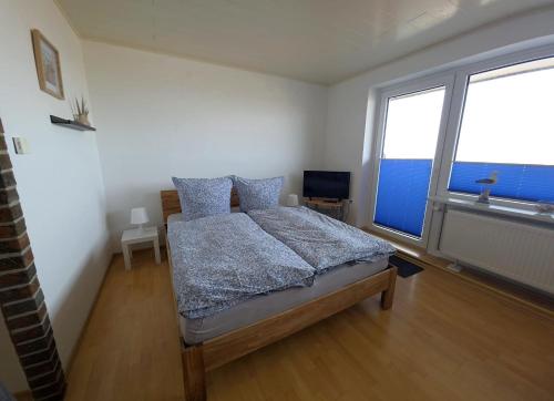 a bedroom with a bed and a large window at Tief 10 Austernfischer 708 in Wangerland