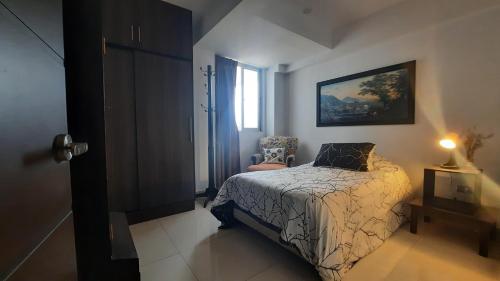 a bedroom with a bed and a chair and a window at Apartamento moderno y comodo in Cochabamba