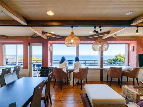 two women sitting at a table in a restaurant looking out at the ocean at UMI SORA VILLA 伊豆河津 in Kawazu