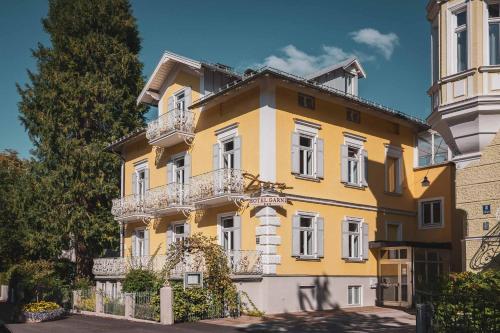 a yellow building with white windows and a fence at Villa Dora Petit Hôtel in Bad Reichenhall