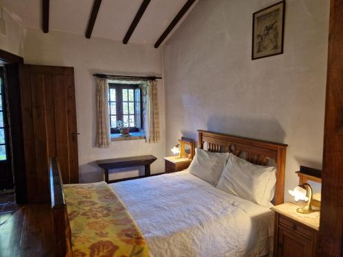 a bedroom with a bed and two tables and a window at Casa Grande - Casas de Campo na Serra da Estrela in Paços da Serra