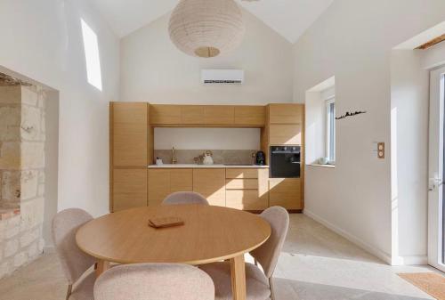 a kitchen and dining room with a wooden table and chairs at La Maison Léoncine in Allonnes