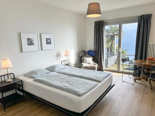 a bedroom with a bed and a table and a window at Casa Rondinella by fewotessin in Orselina