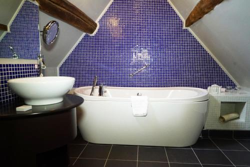 a bathroom with a tub and a toilet and blue tiles at Cotswold House Hotel and Spa - "A Bespoke Hotel" in Chipping Campden