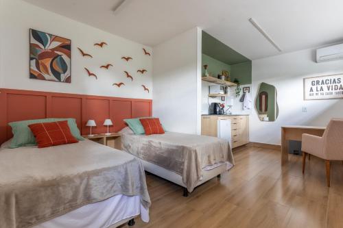 a bedroom with two beds and a desk and a kitchen at Studio Andorinhas in Brasília
