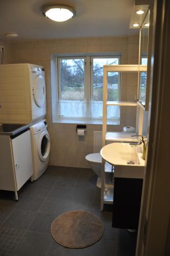 een badkamer met een wastafel en een wasmachine. bij The Gardener House - Grönsöö Palace Garden in Grönsöö