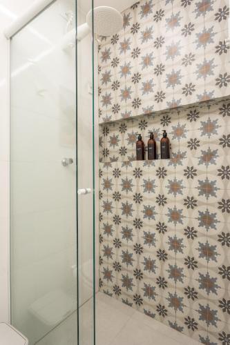 a bathroom with a shower with bottles on a wall at Studio Andorinhas in Brasília