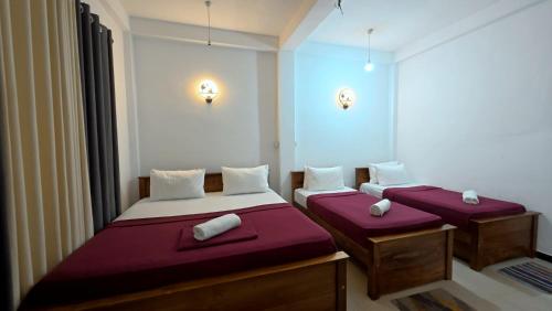 two beds in a small room with red sheets at Akshayaam Villa in Kotagala