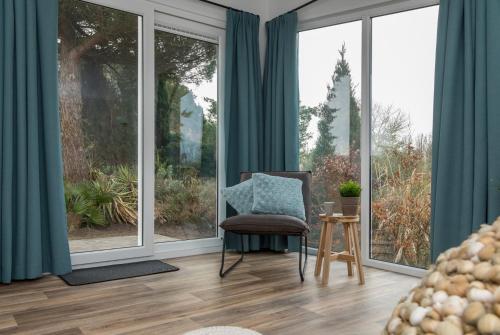 a room with a chair and large windows at Welcome in - Vakantiepark Fort den Haak - 2 huisdieren toegestaan - Dichtbij strand en Veerse Meer in Vrouwenpolder