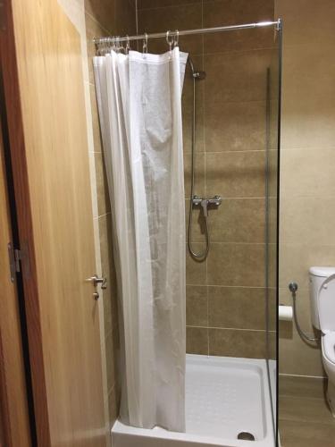 a shower with a white shower curtain in a bathroom at Albergue La Perala in Bercianos del Real Camino