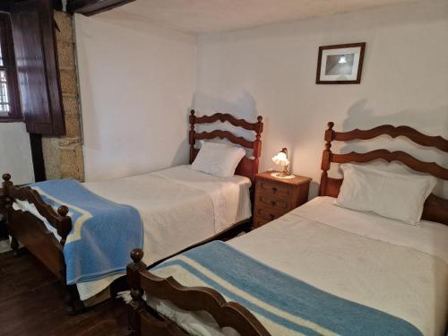 a bedroom with two beds and a night stand with a lamp at Casa Grande - Casas de Campo na Serra da Estrela in Paços da Serra