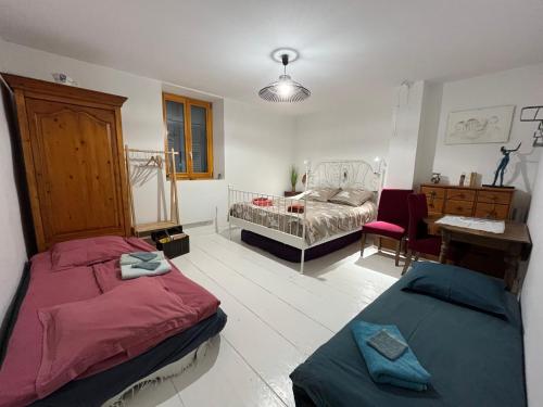 a room with two beds and a bedroom with a desk at La Cocotte Rousse, ses Petits Déjeuners et sa Table in Parves