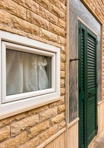 a window on a brick building with a green shutter at Gallipoli - Suite Levante in Gallipoli