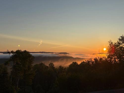a view of the sun rising over a foggy valley at Chalet Le Valkea - Spa & Mountain in Saint Come