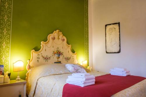 a bedroom with a white bed with a green wall at Dimora del Passaggio in Castiglion Fiorentino