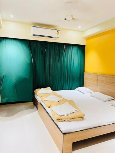 a bedroom with two beds and a green curtain at HOTEL MADNI ROYALE (50 Mtrs from Dargaah), Ajmer in Ajmer