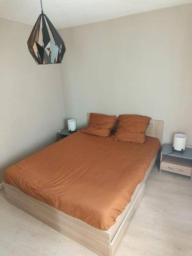 a bedroom with a large bed with orange sheets at Small townhouse in Clermont-Ferrand