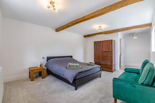 a bedroom with a bed and a green couch at 5 Bed in Roxwell oc-t30824 in Roxwell
