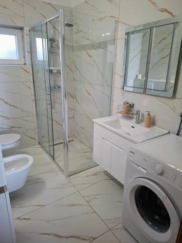 a bathroom with a washing machine and a washer at Apartman TRALJE in Senj