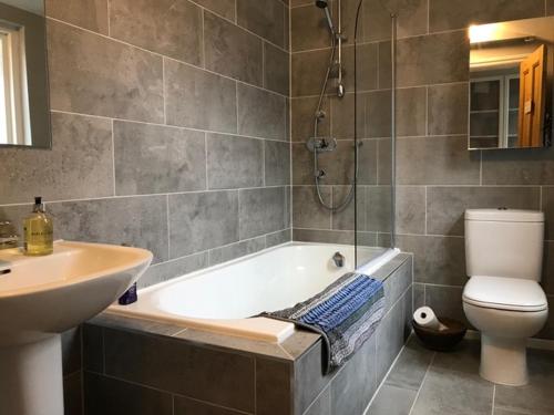 a bathroom with a tub and a toilet and a sink at Stunning 3 bed house by Endcliffe Park in Nether Edge