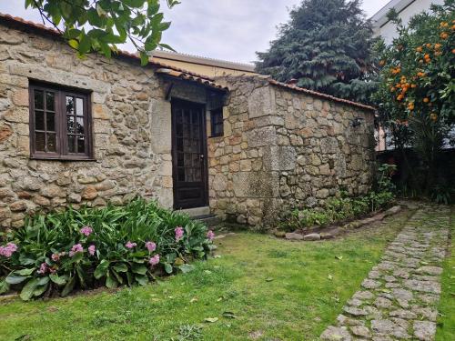 a stone house with a door and some flowers at Casa Grande - Casas de Campo na Serra da Estrela in Paços da Serra