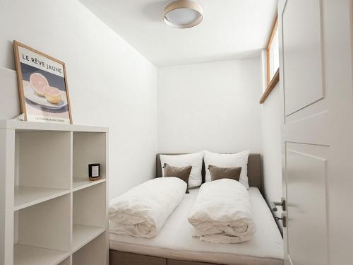 a small bedroom with a bed with white sheets and pillows at Ferienwohnung Ufertraum am Dümmer See in Lembruch