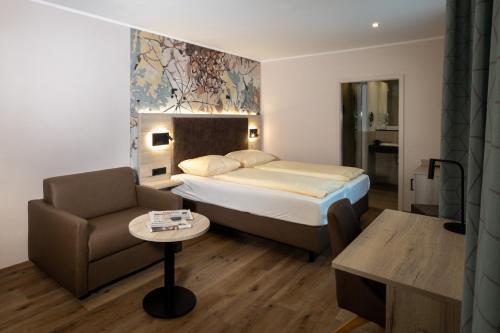 een hotelkamer met een bed en een stoel bij Hotel-Restaurant Dimmer - Mullerthal in Wallendorf pont